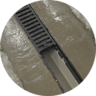 Black drain grate set into a wet concrete floor