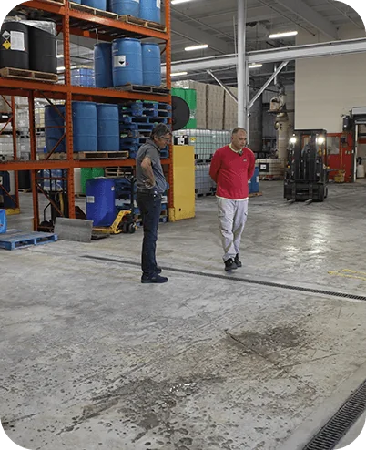Two workers inspecting a warehouse floor drainage route