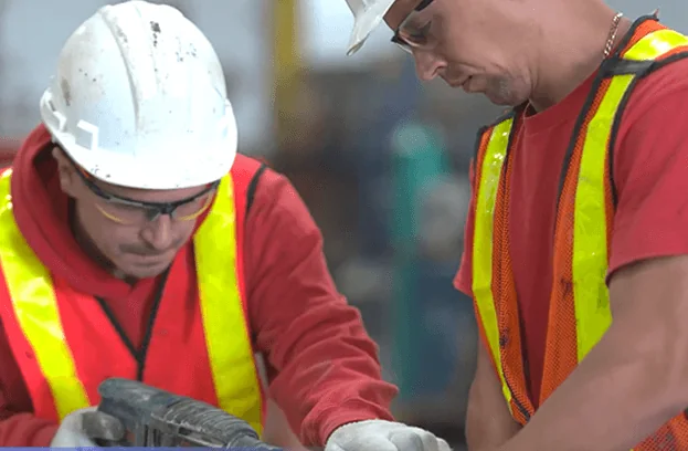 Two installers examining drainage materials in a workshop