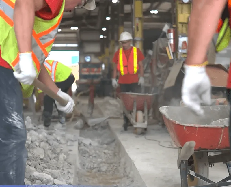 Crew placing concrete around a floor drainage trench