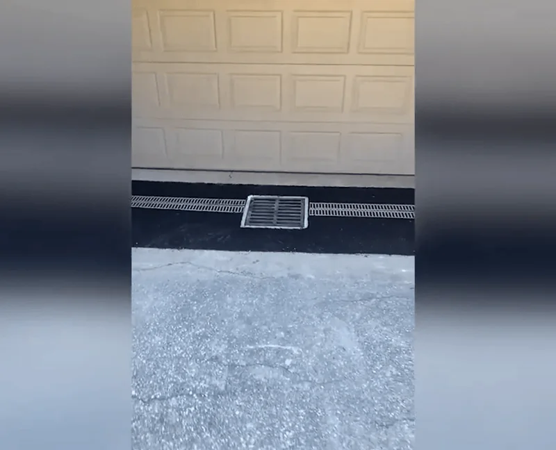 Drain grate in front of a residential garage door